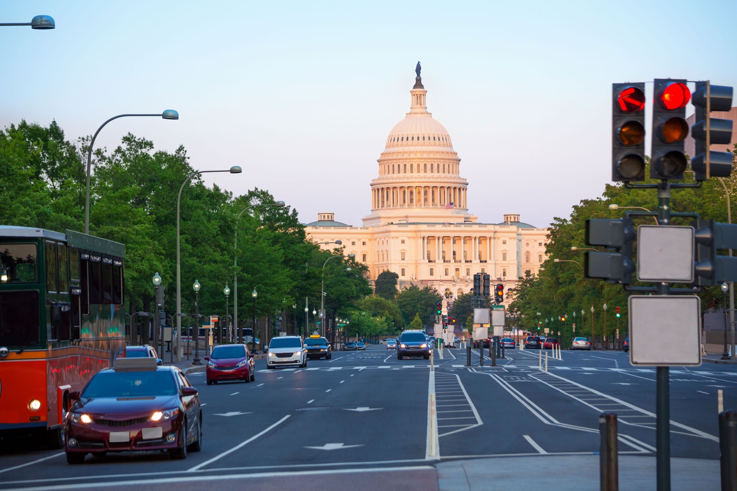 View of the U.S. Capitol down a busy road during sunset.