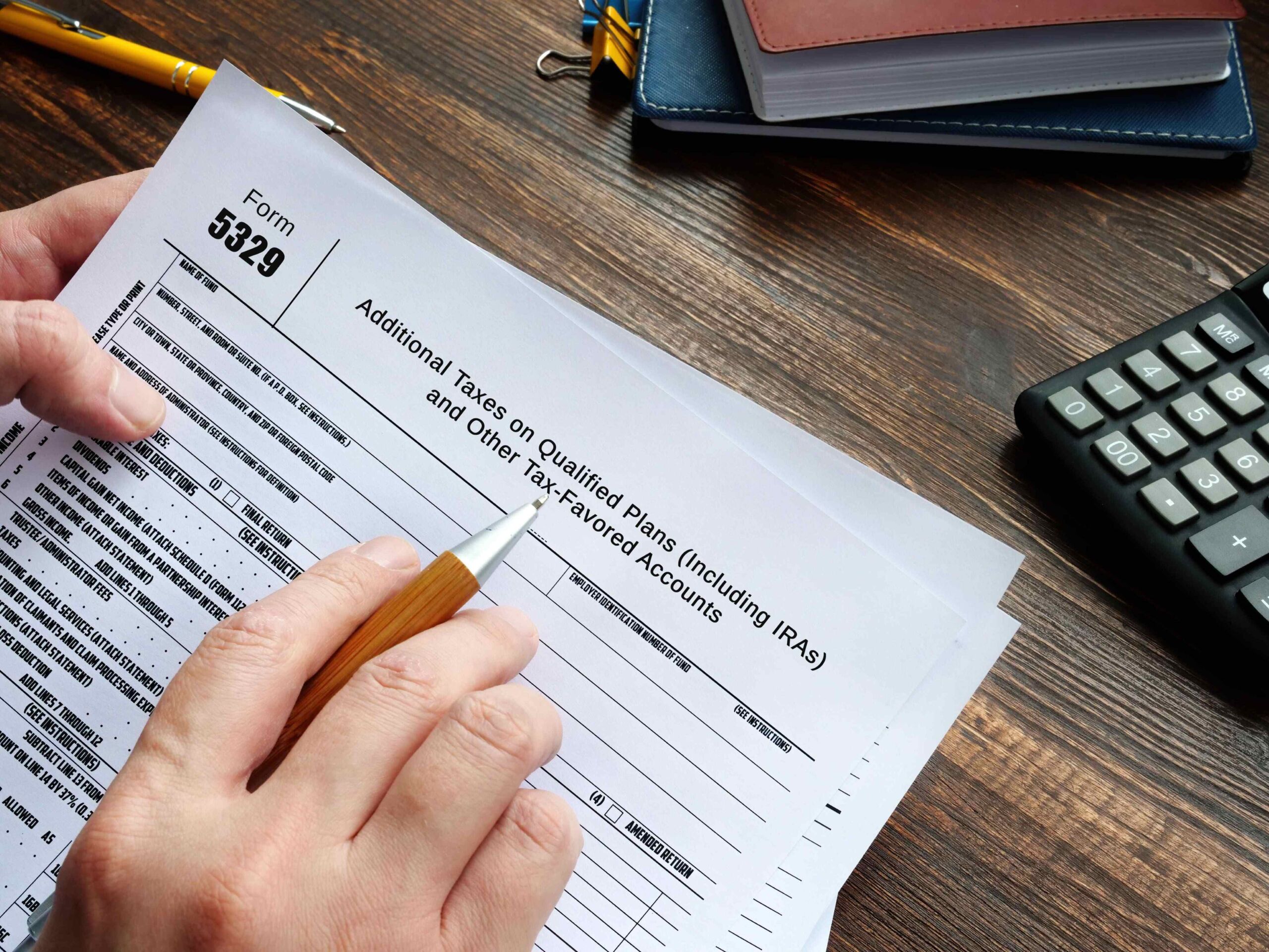 Closeup of an accountant filling out a paper Form 5329.